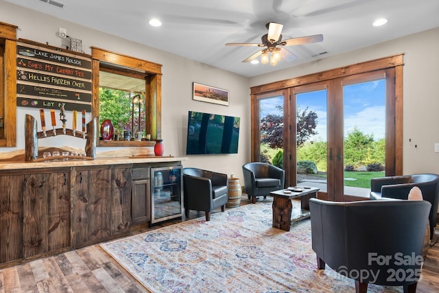 living room featuring beverage cooler, bar with sink, wood finished floors, a ceiling fan, and recessed lighting