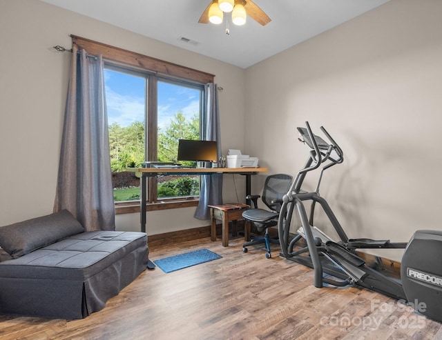 exercise area featuring wood finished floors, ceiling fan, and baseboards