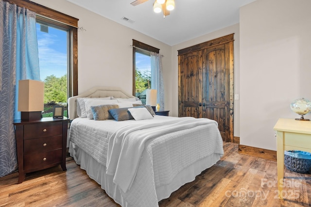 bedroom with light wood-style flooring, a ceiling fan, and baseboards
