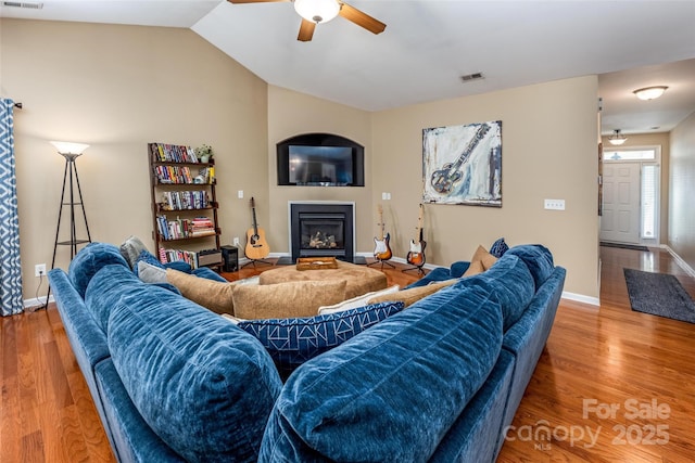 19539 Denae Lynn Dr, Cornelius, NC 28031 - living area featuring a ceiling fan, a glass covered fireplace, wood finished floors, baseboards, and vaulted ceiling