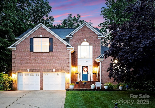 traditional home featuring driveway, brick siding, a garage, and a front lawn