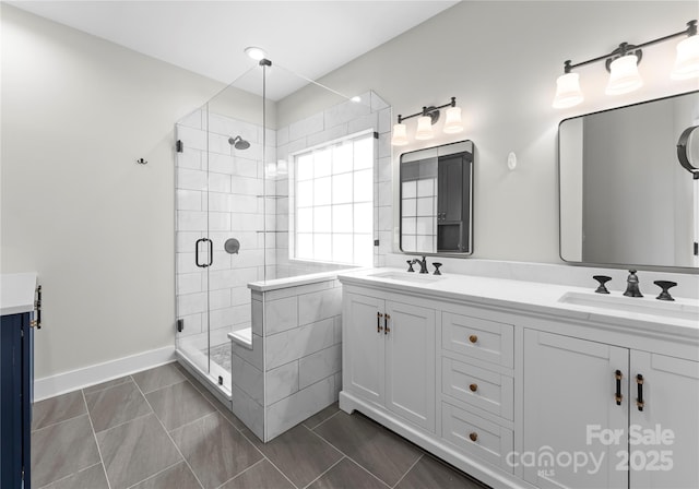 full bathroom with a shower stall, double vanity, tile patterned flooring, and baseboards