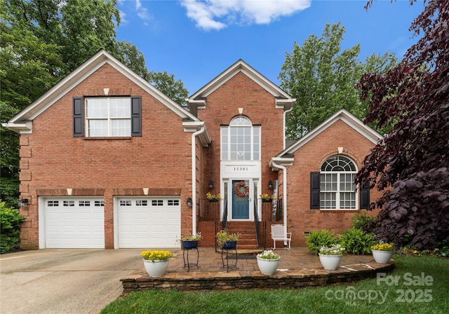 traditional-style house featuring driveway, brick siding, and a garage