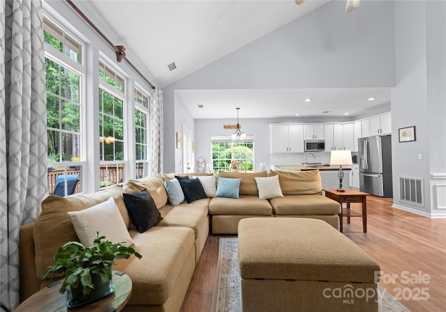 living area featuring high vaulted ceiling and light wood-style floors