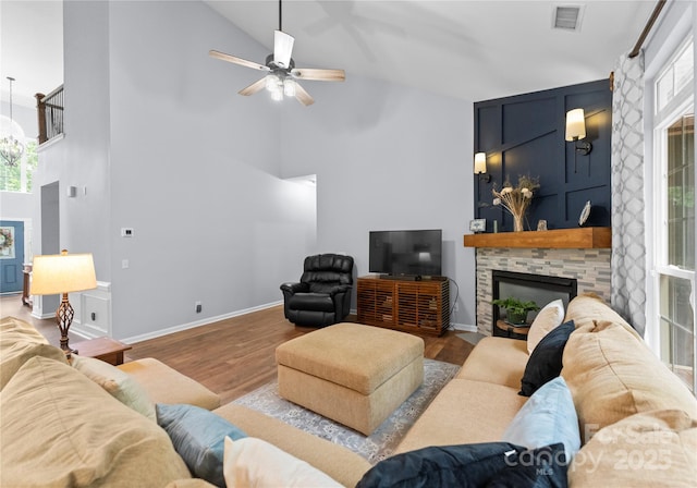 living area featuring high vaulted ceiling, a fireplace, plenty of natural light, wood finished floors, and ceiling fan