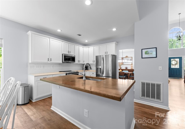 kitchen featuring appliances with stainless steel finishes, a sink, wooden counters, dark wood-style floors, and recessed lighting