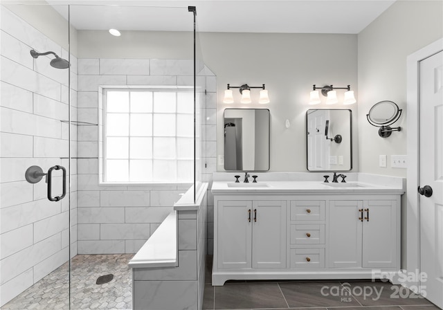 bathroom with tiled shower, plenty of natural light, double vanity, and tile patterned floors