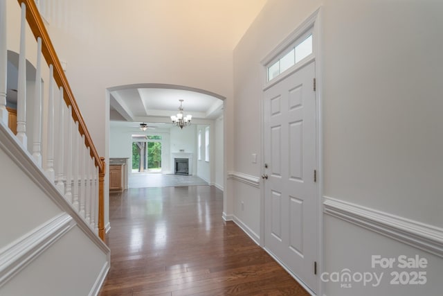 11945 Red Rust Ln, Charlotte, NC 28277 - foyer entrance featuring arched walkways, a tray ceiling, dark wood finished floors, ceiling fan, and a fireplace