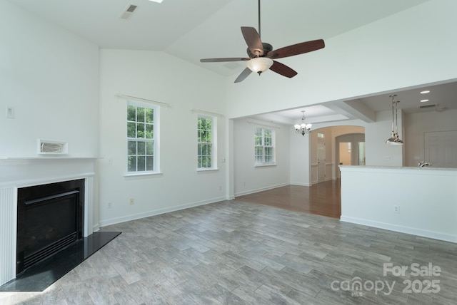 11945 Red Rust Ln, Charlotte, NC 28277 - unfurnished living room featuring a glass covered fireplace, ceiling fan, a chandelier, arched walkways, and wood finished floors
