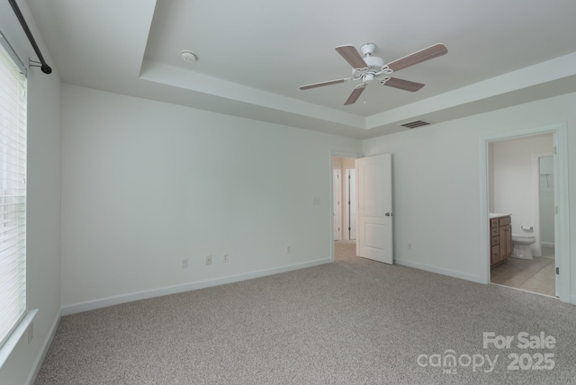 11945 Red Rust Ln, Charlotte, NC 28277 - unfurnished bedroom featuring light colored carpet, a tray ceiling, connected bathroom, and ceiling fan
