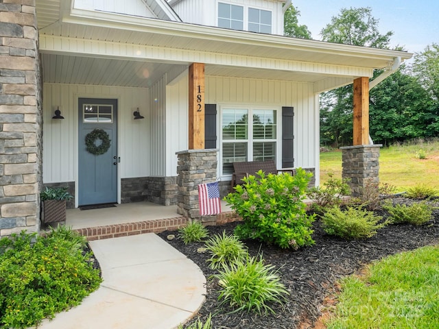 view of exterior entry with stone siding and covered porch