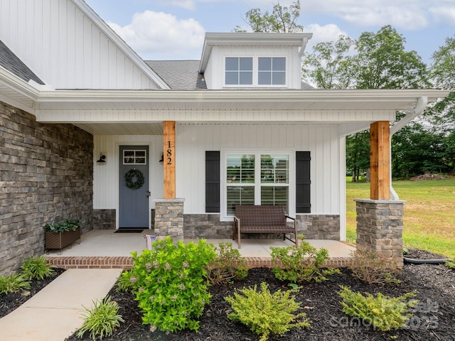 view of front of home with a porch, stone siding, and roof with shingles