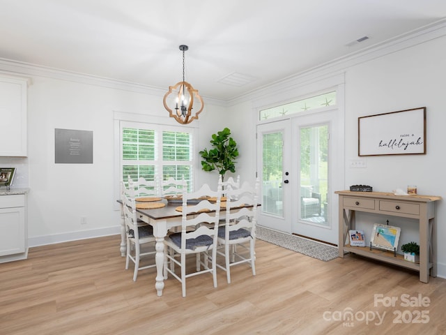 dining space featuring light wood finished floors, a chandelier, crown molding, baseboards, and french doors