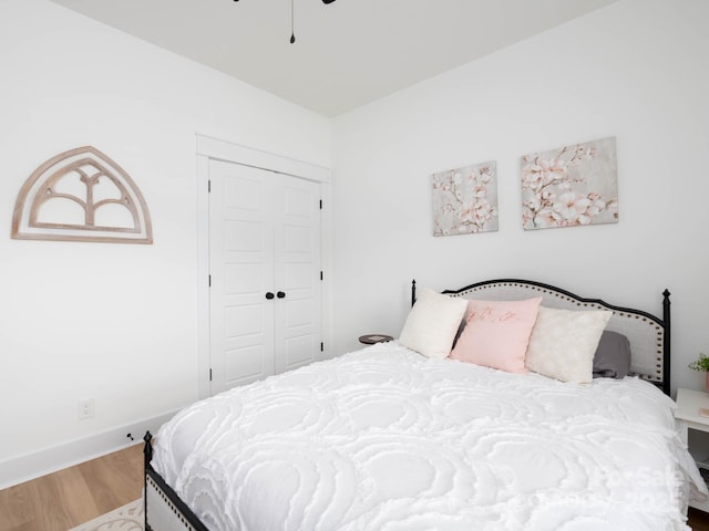 bedroom with wood finished floors, a closet, baseboards, and ceiling fan