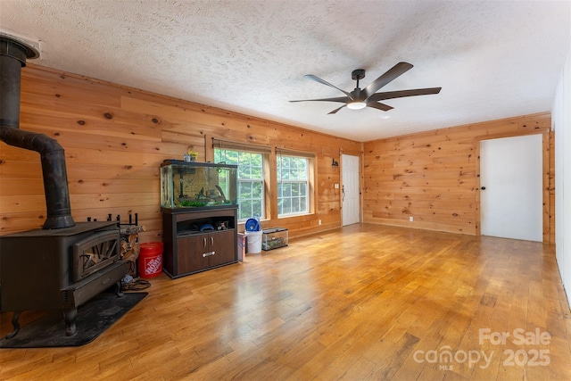 116 Hidden Meadow Dr Unit 17, Candler, NC 28715 - living room featuring a wood stove, a ceiling fan, wood finished floors, wooden walls, and a textured ceiling
