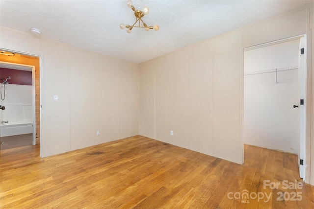 116 Hidden Meadow Dr Unit 17, Candler, NC 28715 - unfurnished bedroom with light wood-style flooring, a spacious closet, a closet, and a textured ceiling
