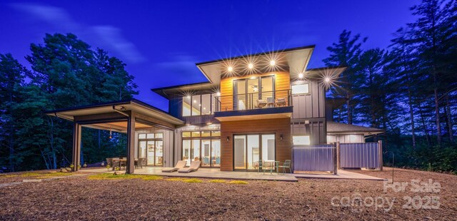 223 Linville View Dr, Nebo, NC 28761 - back of house at night with a balcony, french doors, a patio, and board and batten siding