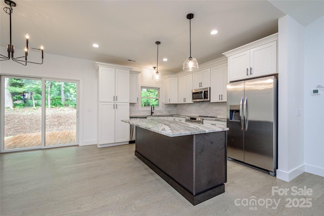 118 W Laurel Ln, Etowah, NC 28729 - kitchen with appliances with stainless steel finishes, light wood finished floors, light stone counters, a kitchen island, and a chandelier