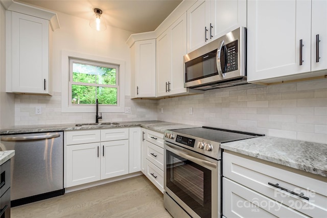 118 W Laurel Ln, Etowah, NC 28729 - kitchen with appliances with stainless steel finishes, white cabinetry, light stone countertops, and tasteful backsplash