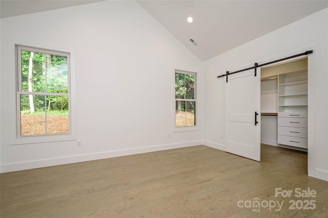 118 W Laurel Ln, Etowah, NC 28729 - unfurnished bedroom featuring a barn door, high vaulted ceiling, light wood-style floors, a spacious closet, and recessed lighting