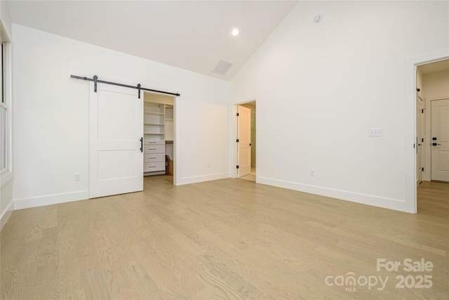 118 W Laurel Ln, Etowah, NC 28729 - unfurnished bedroom featuring a barn door, light wood finished floors, high vaulted ceiling, a walk in closet, and recessed lighting