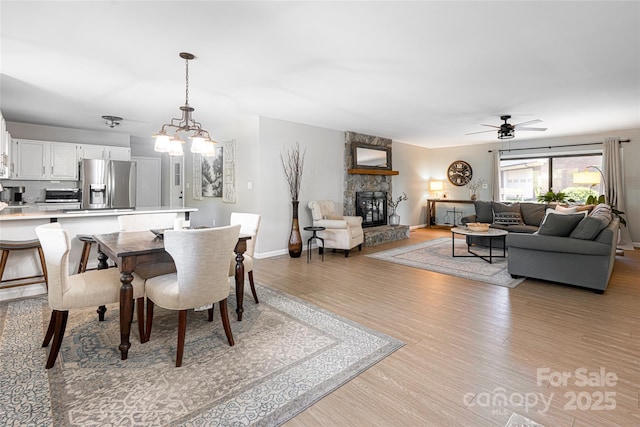 16 Royal Rdg, Clyde, NC 28721 - dining room featuring light wood-type flooring, a stone fireplace, a ceiling fan, and baseboards