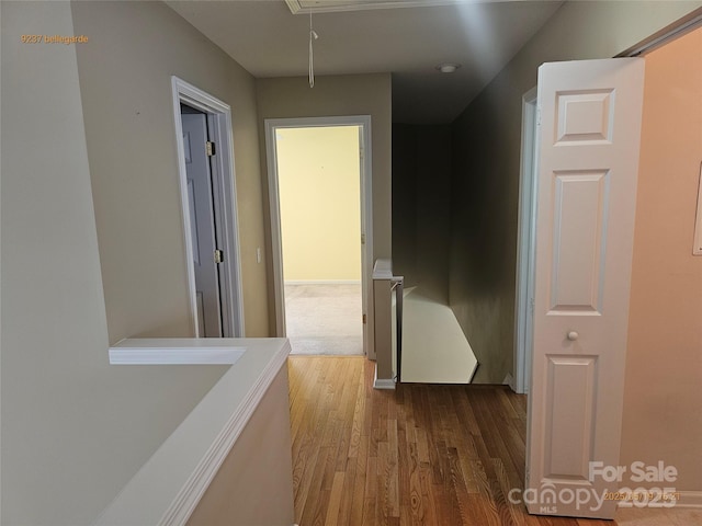 corridor with attic access and wood finished floors