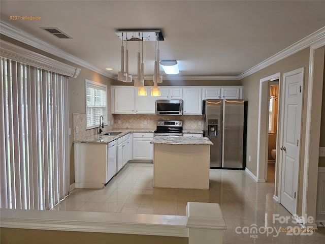 kitchen with appliances with stainless steel finishes, a sink, crown molding, backsplash, and light stone counters