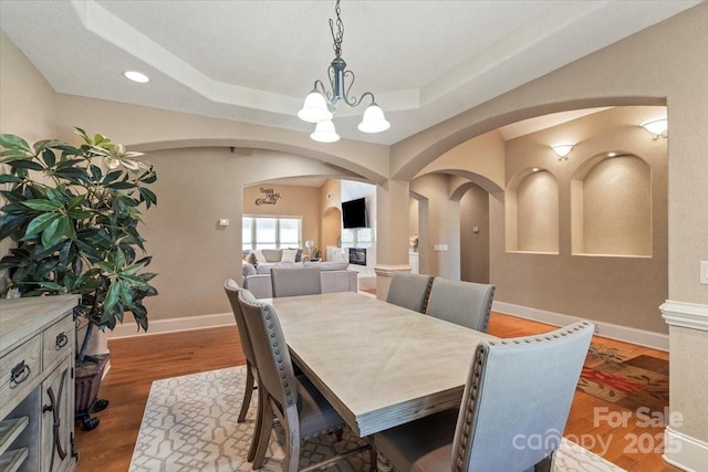 1974 Glen Manor Ct, Lincolnton, NC 28092 - dining room with arched walkways, a chandelier, a raised ceiling, wood finished floors, and baseboards