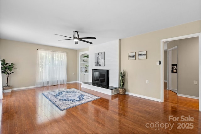 220 Pinehurst Ln, Newton, NC 28658 - unfurnished living room with built in features, ceiling fan, wood finished floors, a large fireplace, and baseboards