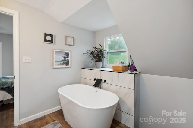 1135 Brook Path Trl, Denver, NC 28037 - ensuite bathroom with wood finished floors, a freestanding bath, vaulted ceiling, and baseboards