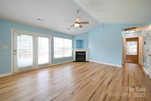 unfurnished living room with lofted ceiling, light wood-type flooring, ceiling fan, baseboards, and a fireplace with flush hearth