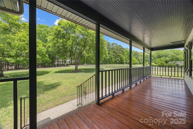 deck with a porch, view of scattered trees, and a lawn