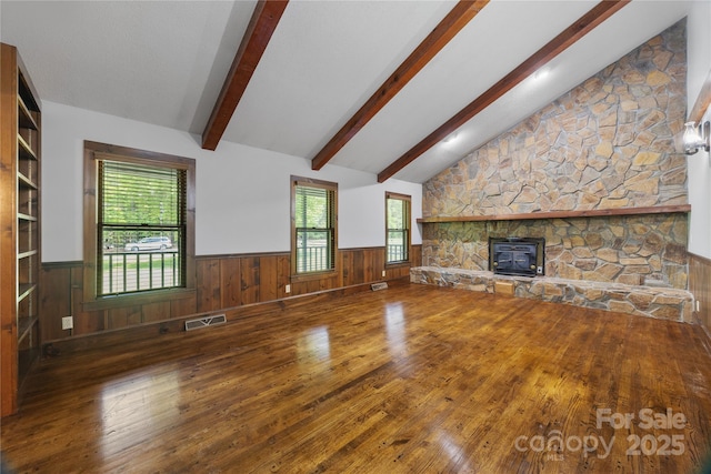 unfurnished living room with hardwood / wood-style flooring, a wainscoted wall, and plenty of natural light