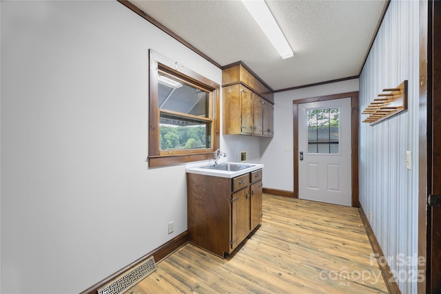 laundry area with cabinet space, hookup for a washing machine, light wood finished floors, baseboards, and a textured ceiling