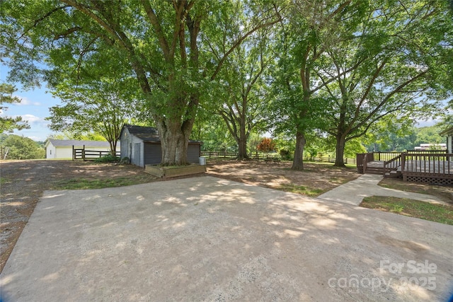 view of yard with fence, an outdoor structure, a shed, and a deck