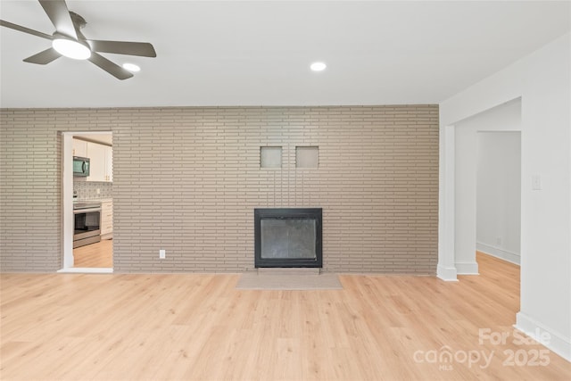 518 Westside Cir, China Grove, NC 28023 - unfurnished living room featuring a fireplace, brick wall, ceiling fan, light wood-style floors, and baseboards
