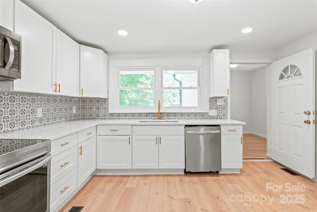 518 Westside Cir, China Grove, NC 28023 - kitchen featuring appliances with stainless steel finishes, a sink, light countertops, white cabinets, and light wood finished floors
