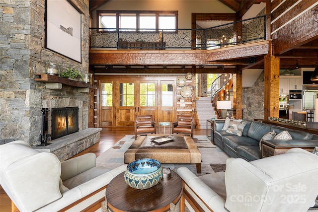511 Asgi Trl, Maggie Valley, NC 28751 - living room featuring high vaulted ceiling, hardwood / wood-style flooring, stairway, a stone fireplace, and beamed ceiling