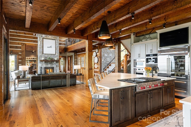 511 Asgi Trl, Maggie Valley, NC 28751 - kitchen featuring stainless steel appliances, a fireplace, light wood-style flooring, wood ceiling with exposed beams, and light countertops