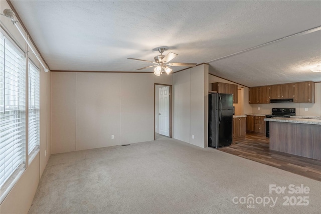 kitchen with black appliances, brown cabinets, dark colored carpet, light countertops, and under cabinet range hood