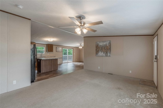 unfurnished living room featuring carpet flooring and ceiling fan