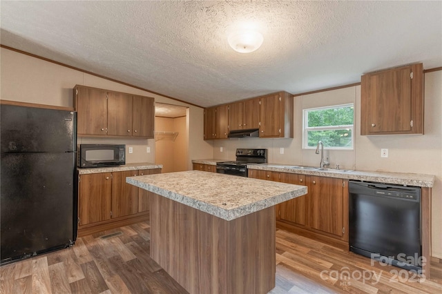 kitchen featuring black appliances, a sink, wood finished floors, a textured ceiling, and light countertops