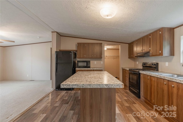 kitchen with black appliances, wood finished floors, light countertops, vaulted ceiling, and brown cabinetry