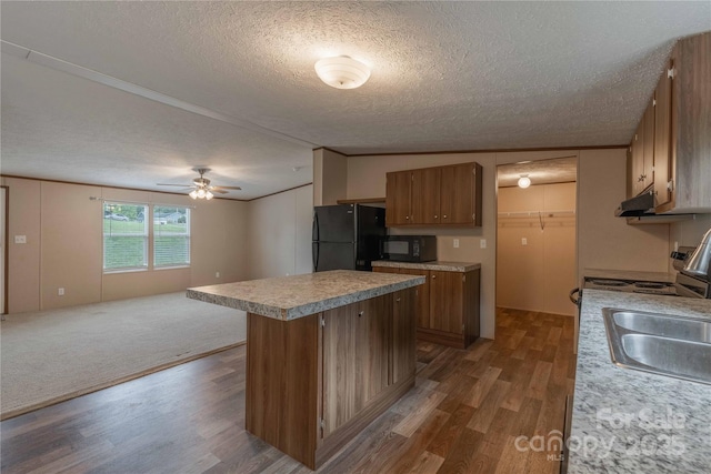 kitchen with black appliances, a textured ceiling, dark wood-style flooring, open floor plan, and light countertops