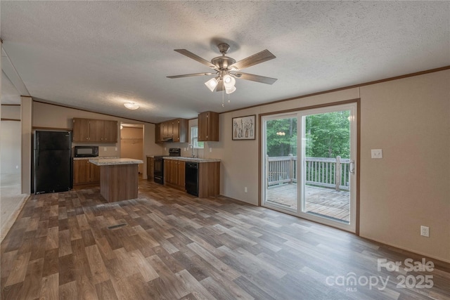 kitchen with black appliances, wood finished floors, light countertops, a textured ceiling, and a ceiling fan