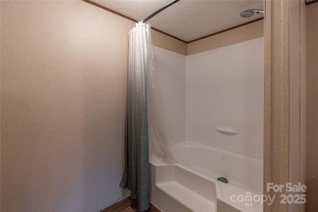 bathroom featuring wood finished floors, shower / bathtub combination with curtain, and a textured ceiling
