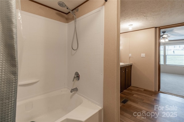 full bath featuring a textured ceiling, wood finished floors, shower / tub combo, vanity, and a ceiling fan