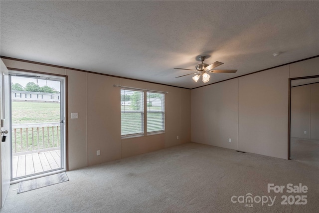 unfurnished living room featuring carpet, a ceiling fan, plenty of natural light, a textured ceiling, and crown molding