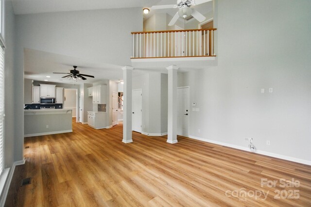 138 Montibello Dr, Mooresville, NC 28117 - unfurnished living room with ceiling fan, high vaulted ceiling, ornate columns, light wood-type flooring, and baseboards